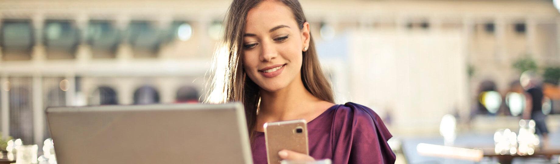 Mulher sorrindo e trabalhando com computador e smartphone